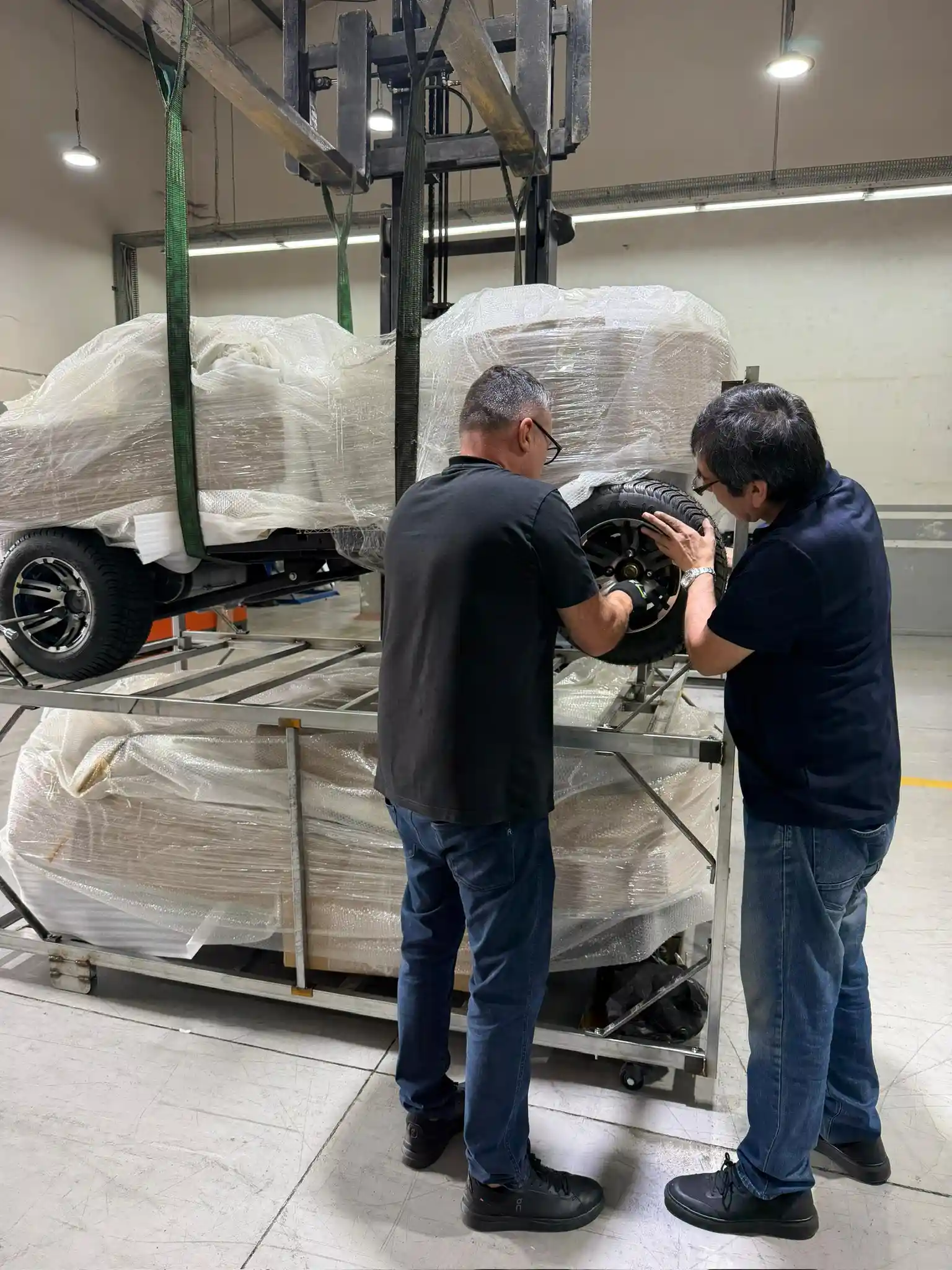 Two G-CART technicians fitting a wheel to a cart in the workshop